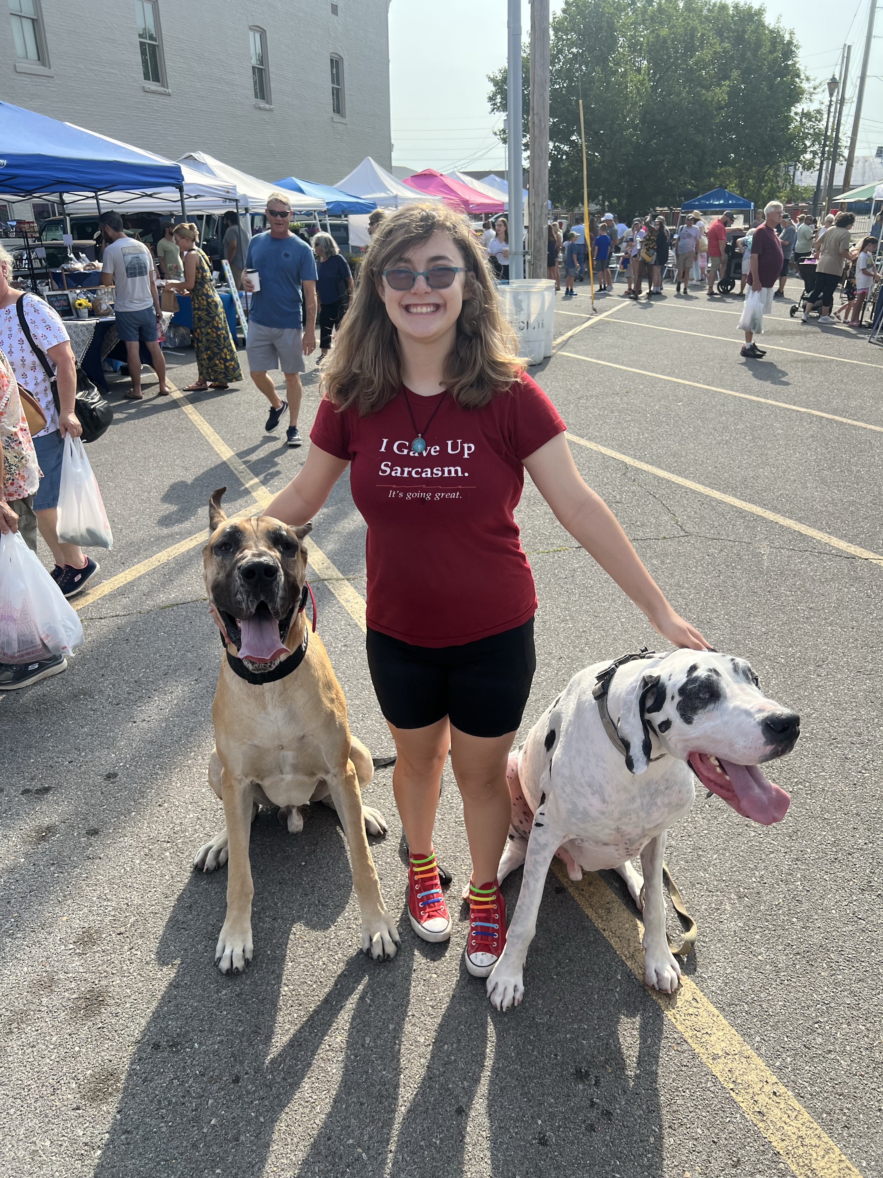 Bella at the Cape Riverfront Market, grinning between two dogs on Spanish Street in Cape Girardeau, Missouri.