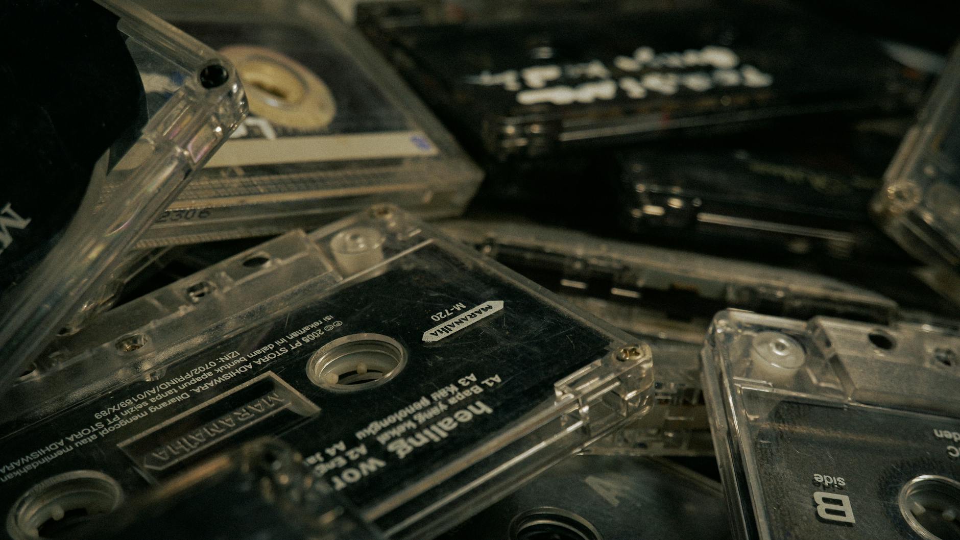 A pile of old cassette tapes in the dark, one visibly labeled "healing"