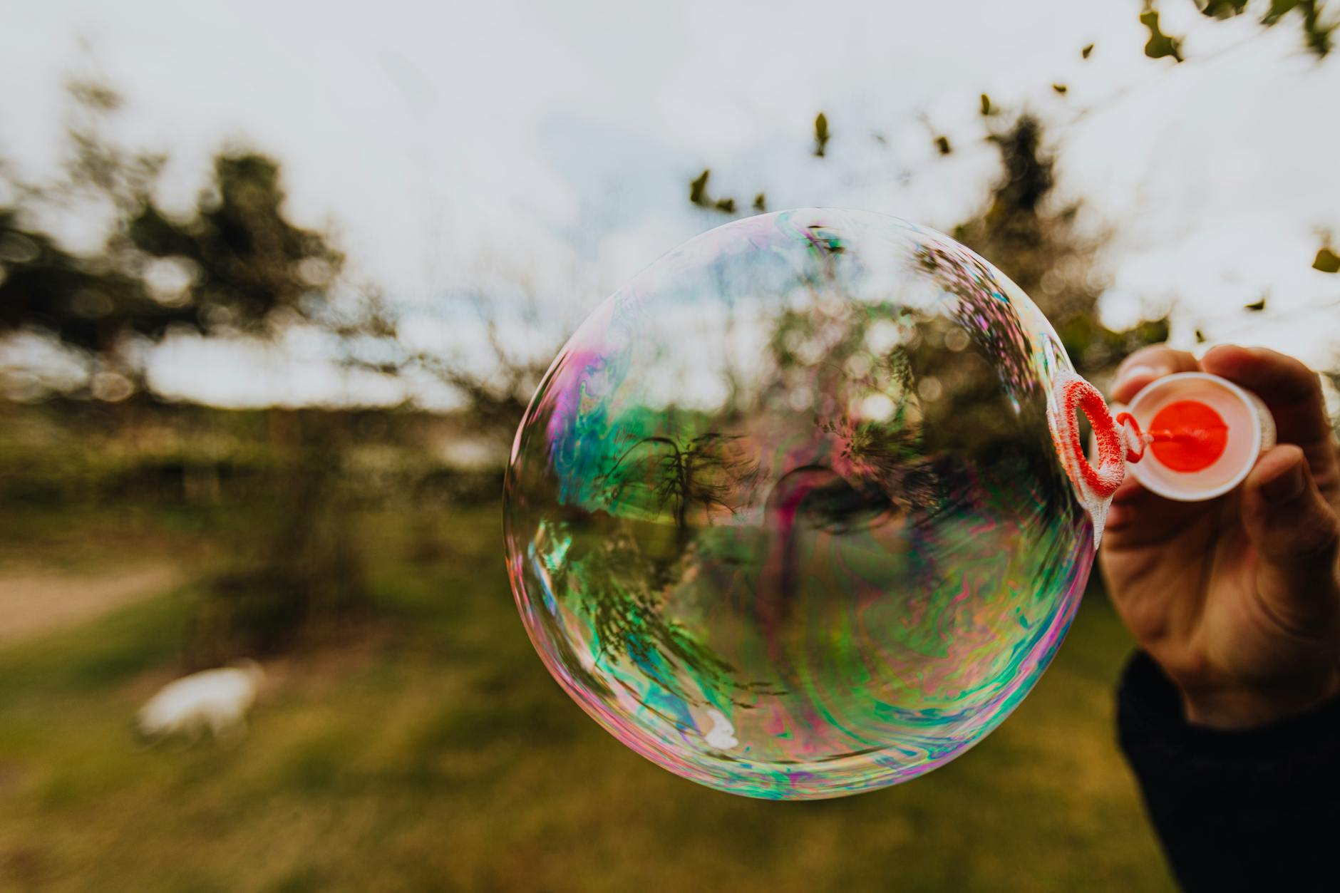 crop person blowing big soap bubble