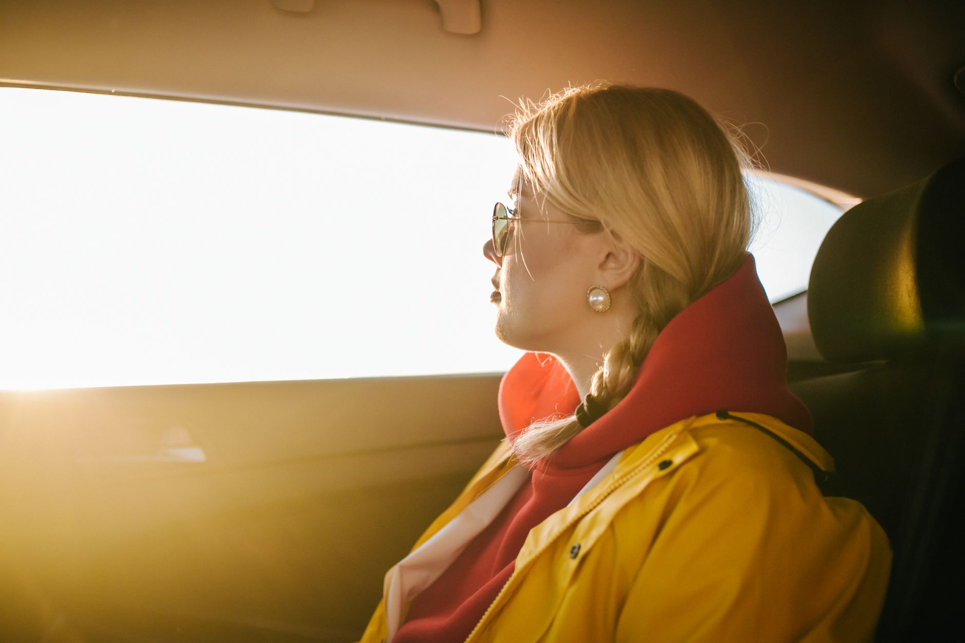 a woman in a yellow jacket looking outside the car window